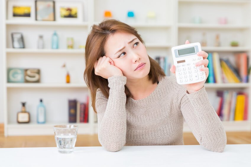 電卓をもって悩む女性